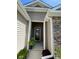 Close-up of a welcoming front entrance with stone and siding details, a decorative wreath, and a potted fern at 234 Rolling Woods Ct., Little River, SC 29566