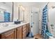 Bright bathroom featuring a double sink vanity and tiled shower with a blue accent at 2487 Windmill Way, Myrtle Beach, SC 29579