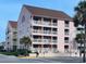 Charming three-story condo with a pink exterior, white railings, balconies, and a well-maintained landscape at 2710 S Ocean Blvd. # 402, Myrtle Beach, SC 29577
