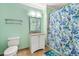 Bright bathroom with a vanity, mirror, toilet, and a shower with a decorative blue shower curtain at 300 N Ocean Blvd. # 122, North Myrtle Beach, SC 29582