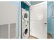 A compact laundry area featuring a stacked washer and dryer unit and a white door at 300 N Ocean Blvd. # 122, North Myrtle Beach, SC 29582
