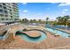 Expansive pool area with a lazy river, beach access, lounge chairs, and tropical landscaping at 300 N Ocean Blvd. # 122, North Myrtle Beach, SC 29582