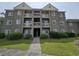 Exterior shot of a multi-story condo building featuring a welcoming entrance, multiple balconies, and lush landscaping at 300-J Myrtle Greens Dr. # J, Conway, SC 29526