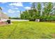 Wide view of the backyard featuring a storage shed, grill, privacy fence, and sprawling lawn at 408 Carmello Circle, Conway, SC 29526