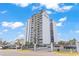 Exterior shot of the Breakers Resort condominium tower with a parking lot and palm trees in the background at 601 Mitchell Dr. # 207, Myrtle Beach, SC 29577
