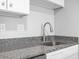 Granite countertop and stainless steel sink with white cabinets in updated kitchen at 601 Mitchell Dr. # 207, Myrtle Beach, SC 29577