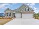 Charming home featuring a two-car garage, brick accents, and light green siding beneath a blue sky at 7175 Shooting Star Way, Myrtle Beach, SC 29579
