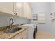 Well-lit laundry room equipped with modern washer and dryer, ample cabinet space, and a granite countertop sink at 7545 Ventura Ct., Myrtle Beach, SC 29572