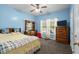 Cozy blue bedroom has a comfortable bed, soft carpet, natural light, and wooden furnishings at 971 Mcnabb Rd., Loris, SC 29569