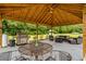 Outdoor living space with a grill, dining table, and seating area beneath a beautiful wood-paneled ceiling at 971 Mcnabb Rd., Loris, SC 29569