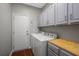 Laundry room with white appliances, cabinets for storage, and tile flooring at 110 Ashworth Dr., Little River, SC 29566