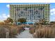 Expansive condominium exterior on a beautiful sunny day with tropical vegetation and sandy beach access at 1105 S Ocean Blvd. # 250, Myrtle Beach, SC 29577