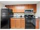 Efficient kitchen with wood cabinets and black appliances including a refrigerator and stove at 1105 S Ocean Blvd. # 250, Myrtle Beach, SC 29577