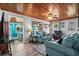 Cozy living room with bright blue sofas, wood ceiling and decor, and an adjacent dining room at 2006 S Ocean Blvd., North Myrtle Beach, SC 29582