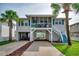 Charming elevated home featuring palm trees, a screened-in porch, and covered parking with stairs leading to the main level at 321 53Rd Ave. N, North Myrtle Beach, SC 29582