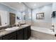 A well-lit bathroom featuring double sinks with granite countertop and a bathtub with tiled surround at 341 Bahama Dr., Murrells Inlet, SC 29576
