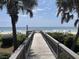 Wooden boardwalk leads to sandy beach, offering tranquil ocean views framed by lush greenery at 371 S Dunes Dr., Pawleys Island, SC 29585