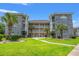 Three-story condo building boasts lovely landscaping, with a winding sidewalk and mature palm trees in front of pale yellow walls at 4687 Wild Iris Dr. # 303, Myrtle Beach, SC 29577