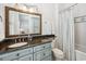 Well-lit bathroom with a blue vanity, granite countertop, tiled walls, a mirror and a shower tub combo at 58 Swan Point Trail, Georgetown, SC 29440