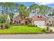 Charming brick home with a manicured lawn, mature trees, and an attached two-car garage at 6434 Longwood Dr., Murrells Inlet, SC 29576