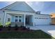 Charming light blue home featuring a two-car garage, covered porch and manicured lawn at 1005 Lady Bird Way, North Myrtle Beach, SC 29582