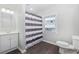 Bright bathroom featuring a modern vanity, striped shower curtain, and wood-look flooring at 1022 Waccamaw Dr., Conway, SC 29526
