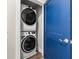Convenient laundry closet with stacked washer and dryer, next to a blue door at 135A Sunset Dr., Murrells Inlet, SC 29576