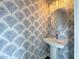 Stylish powder room featuring palm leaf wallpaper and a pedestal sink with a round mirror and modern lighting at 135B Sunset Dr., Murrells Inlet, SC 29576