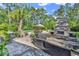 Backyard lounge featuring a stone fireplace, outdoor seating, lush greenery, and a glimpse of the pool at 1662 Westminster Dr., Myrtle Beach, SC 29577