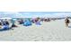 Beach with sunbathers, umbrellas, beach equipment and people walking on a sunny day at 201 74Th Ave. N # 707, Myrtle Beach, SC 29572