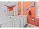 Bathroom with white vanity, dual sinks, and decor on the orange walls at 22 Ocean Blvd. N, Surfside Beach, SC 29575