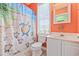 Bright bathroom with orange walls, white vanity, and a shower-tub combo with decorative shower curtain at 22 Ocean Blvd. N, Surfside Beach, SC 29575