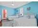 Bright bedroom with two twin beds, a ceiling fan, and light blue walls at 22 Ocean Blvd. N, Surfside Beach, SC 29575