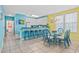 Bright dining area featuring blue furnishings and a glass table, adjacent to a breakfast bar and white cabinetry at 22 Ocean Blvd. N, Surfside Beach, SC 29575