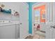 Laundry room with washer, dryer, shelving, and access to bathroom with orange walls and white fixtures at 22 Ocean Blvd. N, Surfside Beach, SC 29575