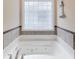 Modern white bathtub with jets, surrounded by tiled walls and a decorative glass block window at 24 Gate 7, Carolina Shores, NC 28467