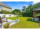This fenced backyard showcases manicured lawn, a gazebo with outdoor dining, and lush tropical landscaping at 309 Foxpath Loop, Myrtle Beach, SC 29588