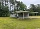 A wide shot of the side of the home with carport and tree-lined landscape at 321 Circle Heights Dr., Loris, SC 29569