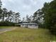 View of the front of the house with an attached carport and surrounding yard with mature trees at 321 Circle Heights Dr., Loris, SC 29569