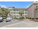 Exterior of a three story yellow condo with brick details and palm trees at 4721 Hibiscus Dr. # 3-302, Little River, SC 29566