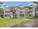 Three-story condo with brick facade, balconies, palm trees, and a well-maintained lawn at 4721 Hibiscus Dr. # 3-302, Little River, SC 29566