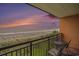 Balcony view of the beach and ocean horizon at sunset, with patio furniture at 6900 N Ocean Blvd. # 421, Myrtle Beach, SC 29572