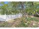 White picket fence enclosing a leafy yard with mature trees and foliage at 910 N Dogwood Dr., Surfside Beach, SC 29575