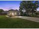 Charming single-story home with white siding, black shutters, long driveway and well-lit windows at dusk at 10071 Kings Rd., Myrtle Beach, SC 29572