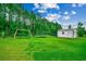 Large grassy backyard featuring a storage shed, playground, and bordered by tall trees at 101 Karlie Ln., Aynor, SC 29511