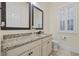 Well-lit bathroom features double mirrors, granite countertop vanity, and toilet with nearby window at 1188 Peterson St., Myrtle Beach, SC 29577