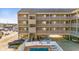 Coastal condo building featuring multiple stories, balconies, ground-level parking, and a refreshing outdoor swimming pool at 120 Dogwood Dr. N # 313, Garden City Beach, SC 29576