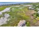 Aerial view of a coastal community showcases buildings, waterway, and marshland with a scenic backdrop at 140 South Cove Pl. # 6C, Pawleys Island, SC 29585