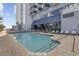 An exterior view of the building's outdoor swimming pool with tables and chairs at 2000 S Ocean Blvd. # V405, Myrtle Beach, SC 29577