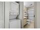 A compact laundry area sits beside a bathroom featuring a shower-tub combination and coordinated shelving at 4344 Spa Dr. # 605, Little River, SC 29566